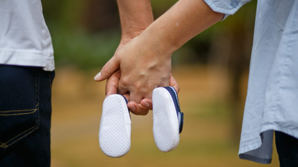 Parents bring home baby shoes holding hands